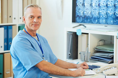 Waist up portrait of modern mature doctor  while posing at workplace with CT scans in background, copy space