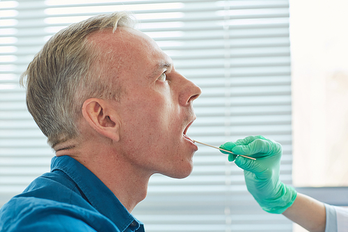 Side view closeup of mature man opening mouth during throat examination in clinic, copy space