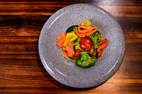 Above view of refreshing salad with salmon on beautiful gray plate on wooden counter