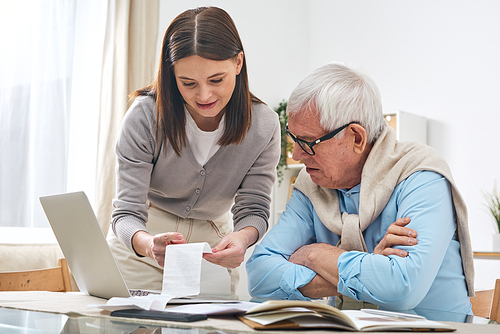 Friendly female social worker explaining check expenses to senior man while he analyzing his budget