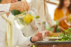 Close up of unrecognizable man pouring lemonade into glass cup while enjoying outdoor party in Summer, copy space