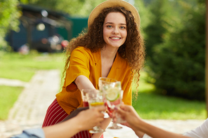 Waist up portrait of smiling young woman toasting with friends while enjoying dinner at outdoor terrace in Summer, copy space