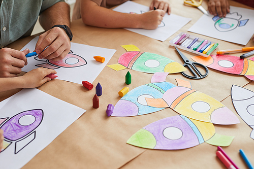 Close up of unrecognizable children drawing pictures of space rockets while enjoying art class in preschool or development center, copy space