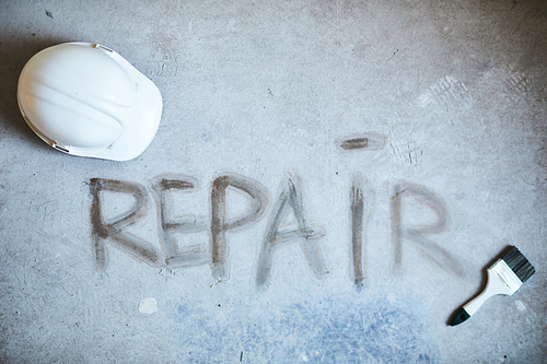 Background image of REPAIR word on concrete floor with building tools in house under construction, copy space
