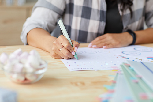 Close up of young mixed-race woman drawing graphs and charts while planning project at home, copy space