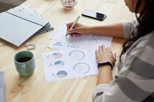 High angle close up of young mixed-race woman drawing graphs and charts while planning project at home, copy space