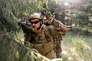 Bearded officer in helmet and sunglasses counting down before attack while conducting military operation in forest