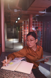 Portrait of contemporary Asian businesswoman working in futuristic office interior, copy space