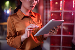 Cropped portrait of contemporary Asian businesswoman using digital tablet while working in futuristic office interior