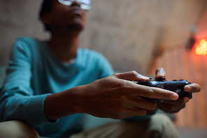 Close up of contemporary African-American man holding gamepad controller while playing videogames