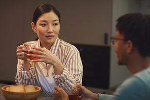 Portrait of ethnic young couple enjoying drinks while chatting at table in cafe