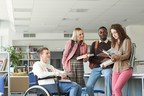 Portrait of multi-ethnic group of students in college library featuring boy in wheelchair in foreground, copy space