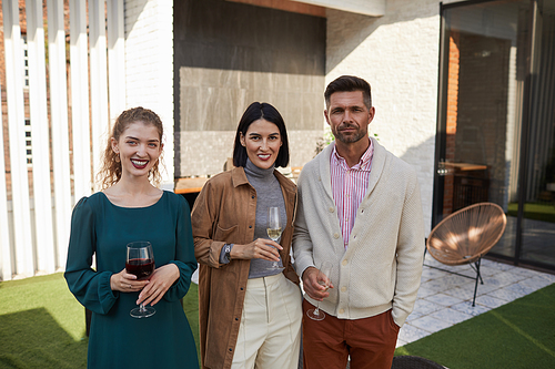 Waist up portrait of contemporary adult people looking at camera and smiling while standing at outdoor terrace, copy space
