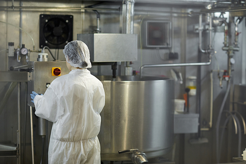 Back view portrait of young female worker operating machine units at clean food production factory, copy space