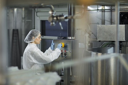 Side view portrait of female worker operating machine units at clean food production factory, copy space