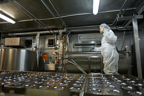 Low angle background image of industrial conveyor belt at clean food production factory with unrecognizable female worker, copy space