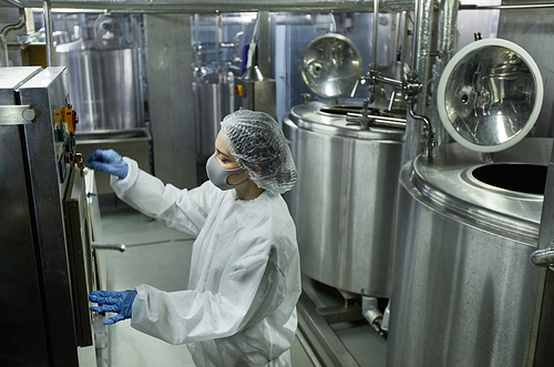 High angle view at young female worker operating machine units while working at clean food factory, copy space