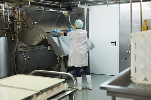 Full length portrait of female worker washing curdling tank in workshop at cheesemaking factory, copy space