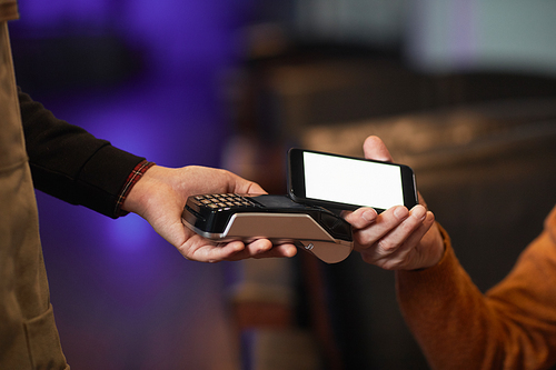 Side view close up of unrecognizable mature man paying via NFC with smartphone, focus on hand holding phone over terminal, copy space