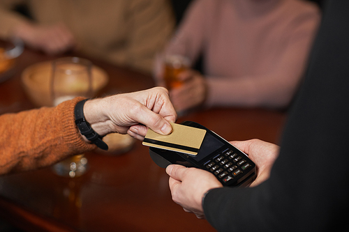 High angle close up of unrecognizable man paying with credit card, focus on hands holding card over terminal, copy space