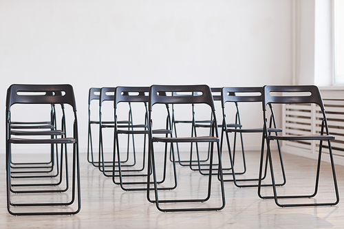 Full length background image of black metal chairs against white background set up for audience at business conference, copy space