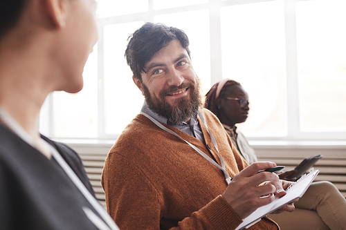 Portrait of smiling bearded man in audience at conference or at business seminar, copy space