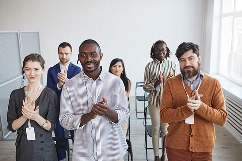 High angle view at multi-ethnic group of business people applauding standing up and smiling in audience at business conference or seminar, copy space