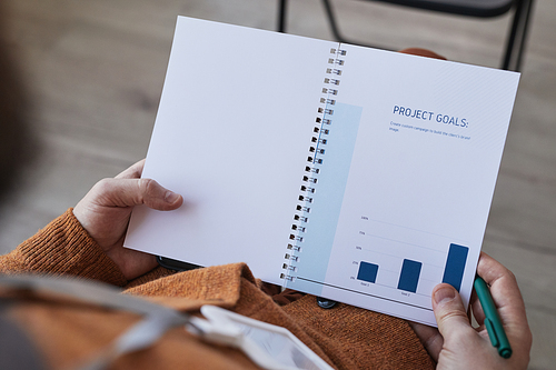 High angle close up of unrecognizable man holding note pad Project goals planner while sitting in audience at business conference, copy space