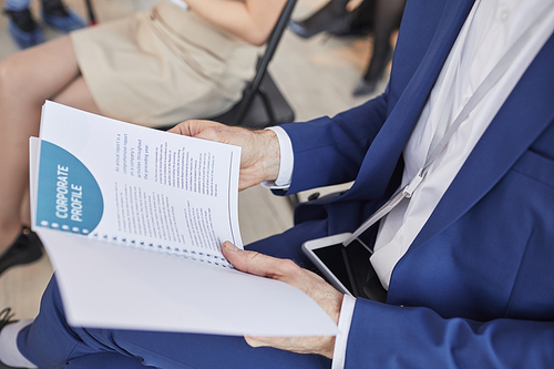 Cropped side view of unrecognizable man holding Project leaflet planner while sitting in audience at business conference, copy space