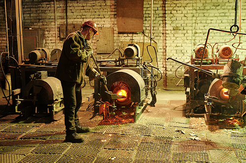 Manual worker melting metal in a furnace for future metal details in the plant