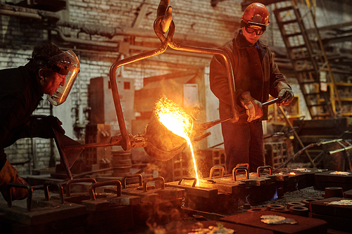 The welder works in the factory shop two steel workers melting metal