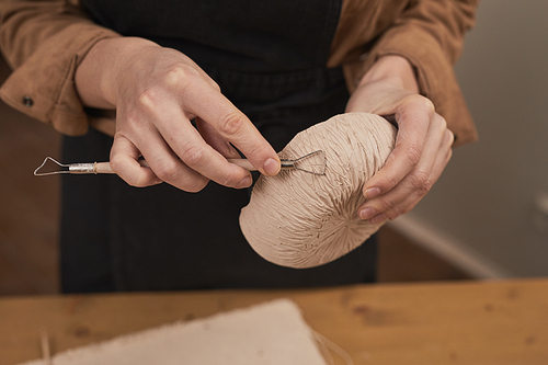 Close up of unrecognizable female potter shaping clay bow in workshop, art hobby and small business concept, copy space