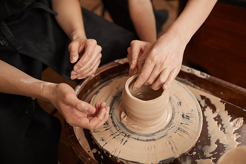 High angle close up of two people shaping clay on pottery wheel, art and craft concept, copy space