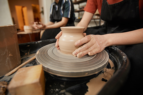 Close up of unrecognizable young woman shaping clay on pottery wheel in workshop while enjoying arts and crafts, copy space