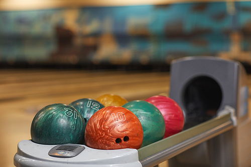 Background image of several bowling balls on rack in bowling alley center, copy space