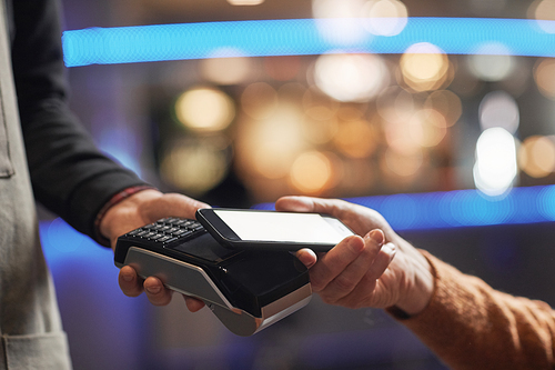 Side view close up of unrecognizable man paying with credit card, focus on hands holding card over terminal, copy space