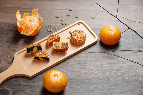 Traditional Chinese mooncakes with various fillings on wooden board on dinner table served for mid autumn festival
