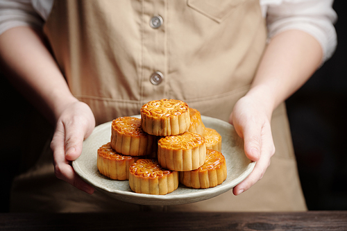 Cook holding plate with freshly baked mooncakes for mid autumn festival