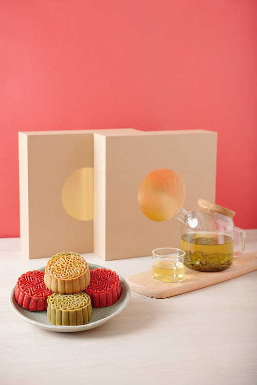 Red, yellow and green mooncakes and pot of green tea served for mid autumn celebration festival