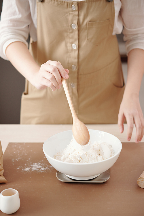 Woman using electronic scale to measure flour for the pastry she is making at home