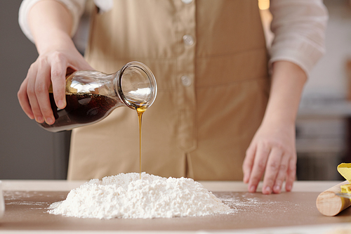 Woman adding golden syrup to flour when making dough for the mooncakes