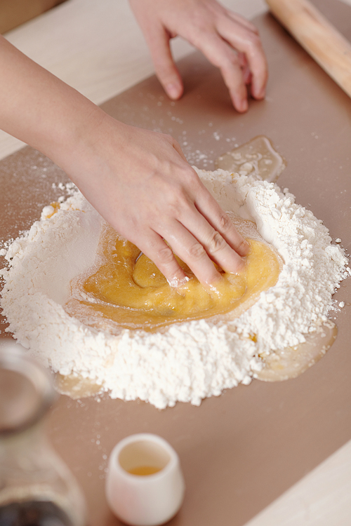 Hands of woman mixing ingredients for mooncake dough on plastic board