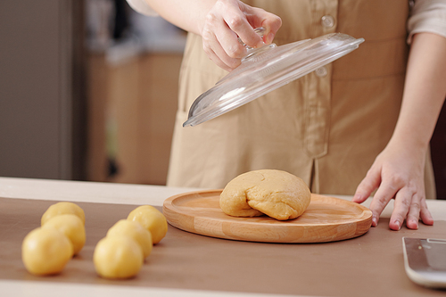 Cropped image of woman covering left piece of dough with lid after making round buns