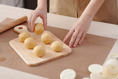Close-up image of woman putting dough buns on wooden cutting board