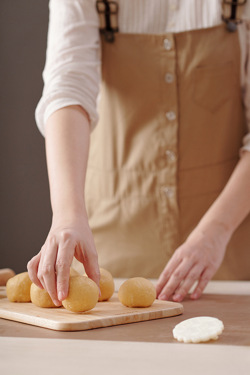 Close-up image of woman putting raw buns with filling on wooden board