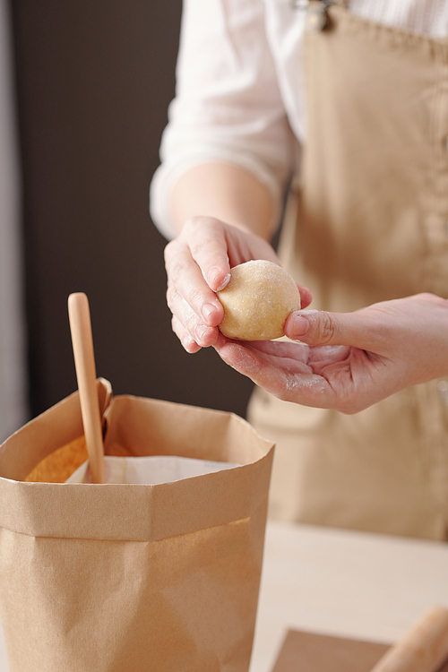 Close-up image of woman covering dough balls with white flour when making mooncakes for celebration