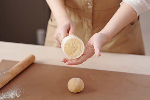 Woman coating plastic mooncake form with flour before using it