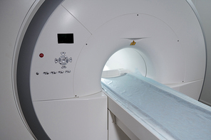 New MRI scan equipment with long table covered with napkin and panel with buttons and small screen