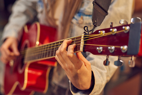 Young female in denim jacket playing guitar