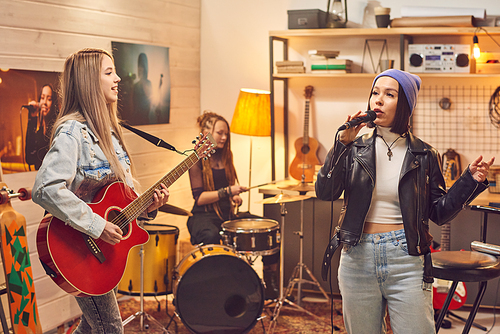 Female band consisting of three girls recording songs in studio